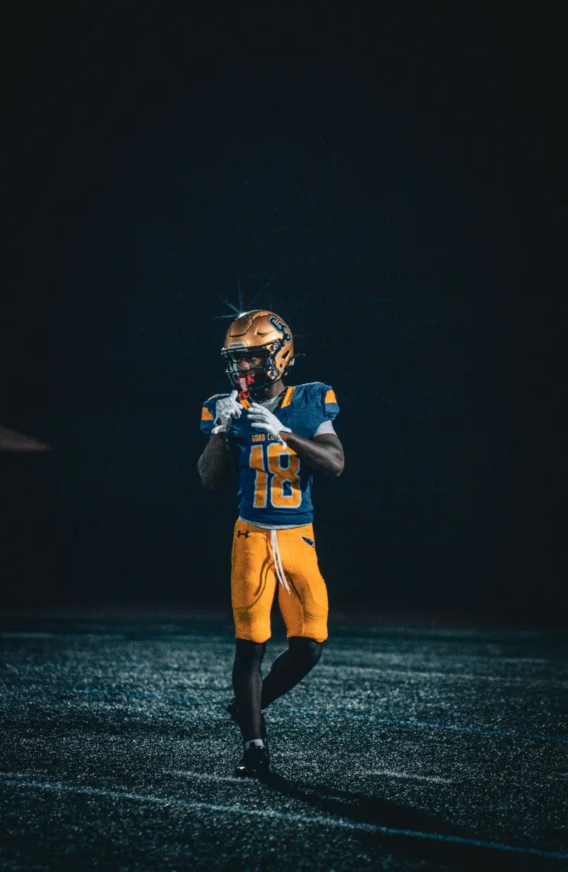 Player number 18 standing alone on the field under the night lights
