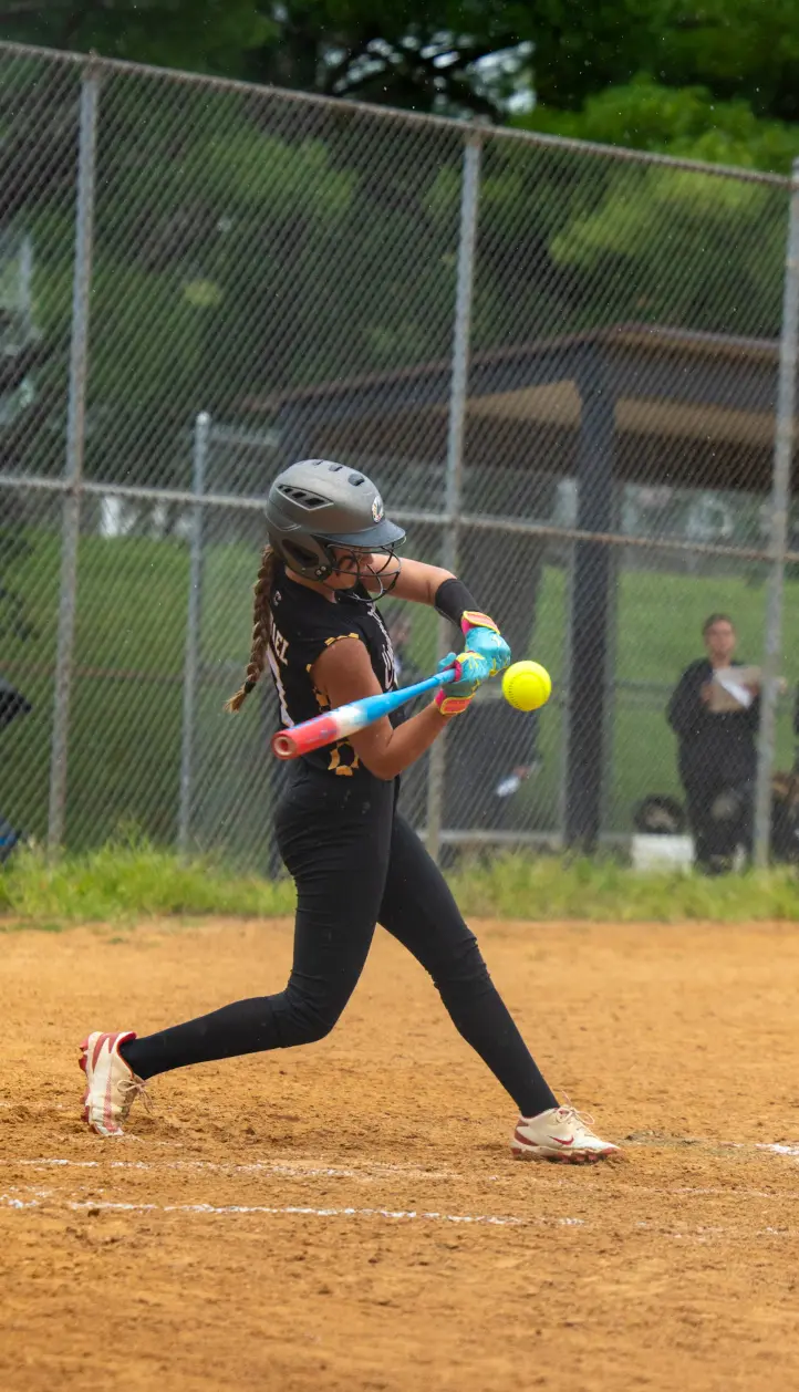 Softball batter swinging at a pitch on a rainy day