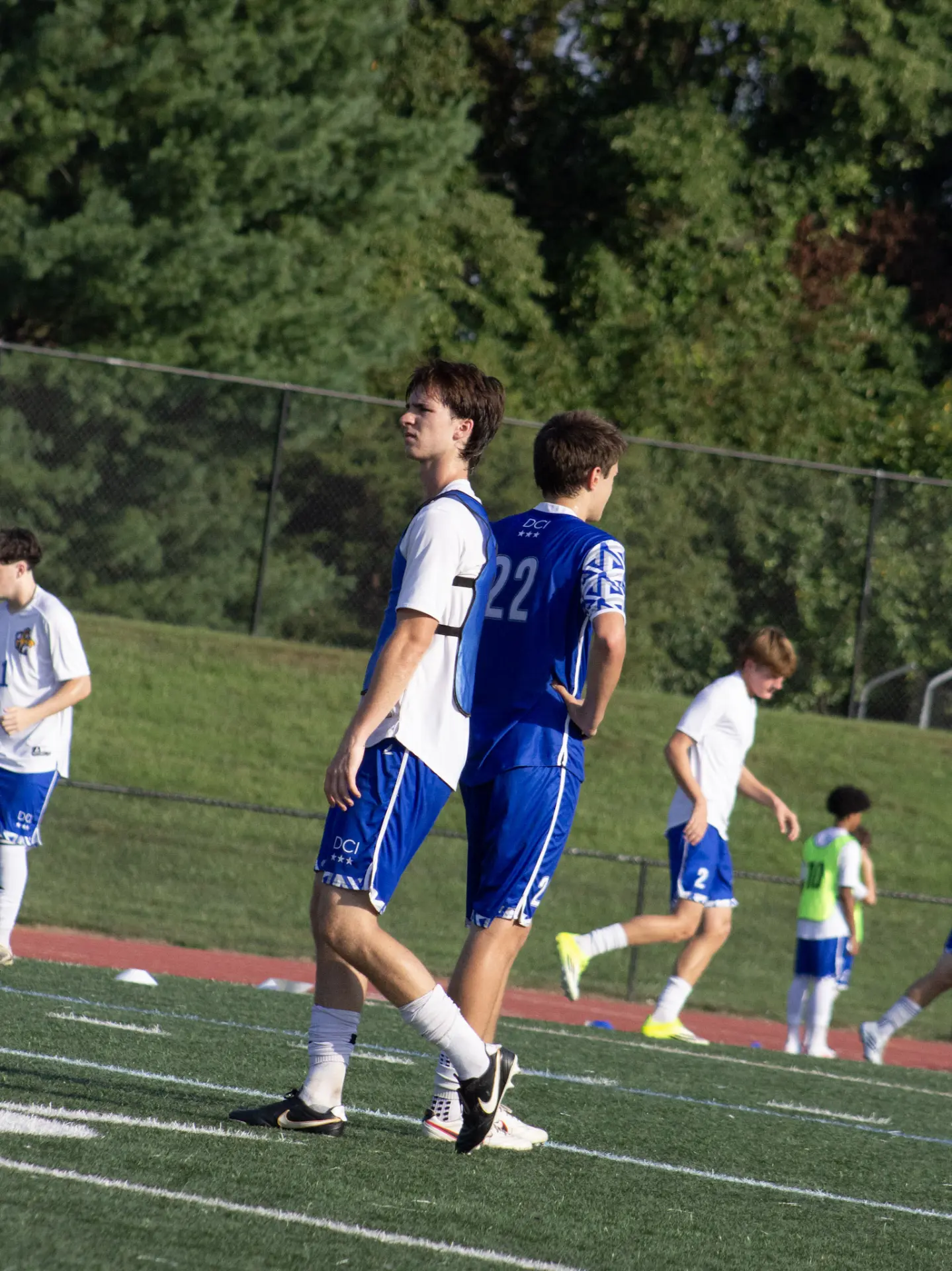 Two soccer players in blue standing back to back at practice