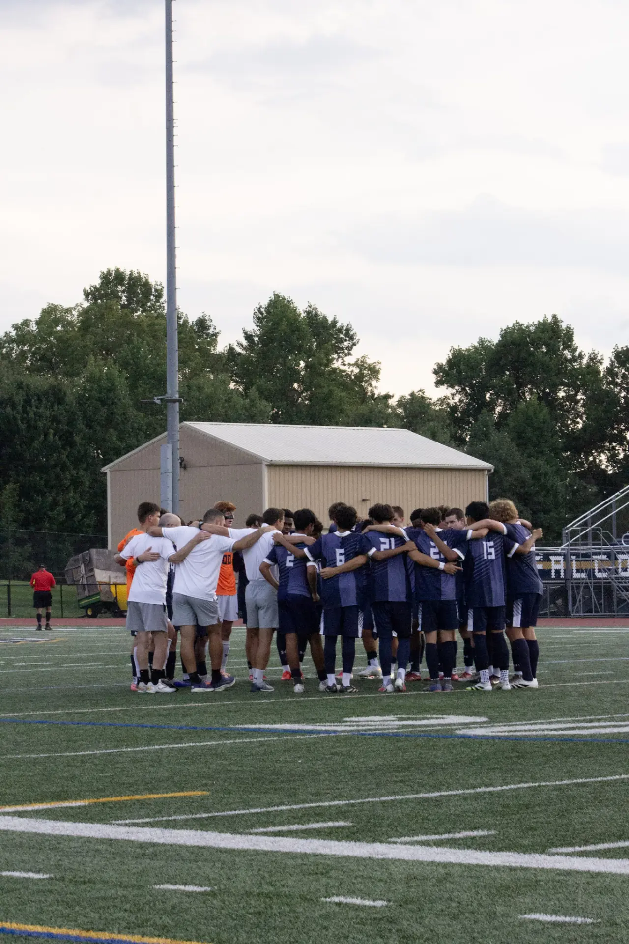 Soccer team huddled together arm in arm on the field before the match