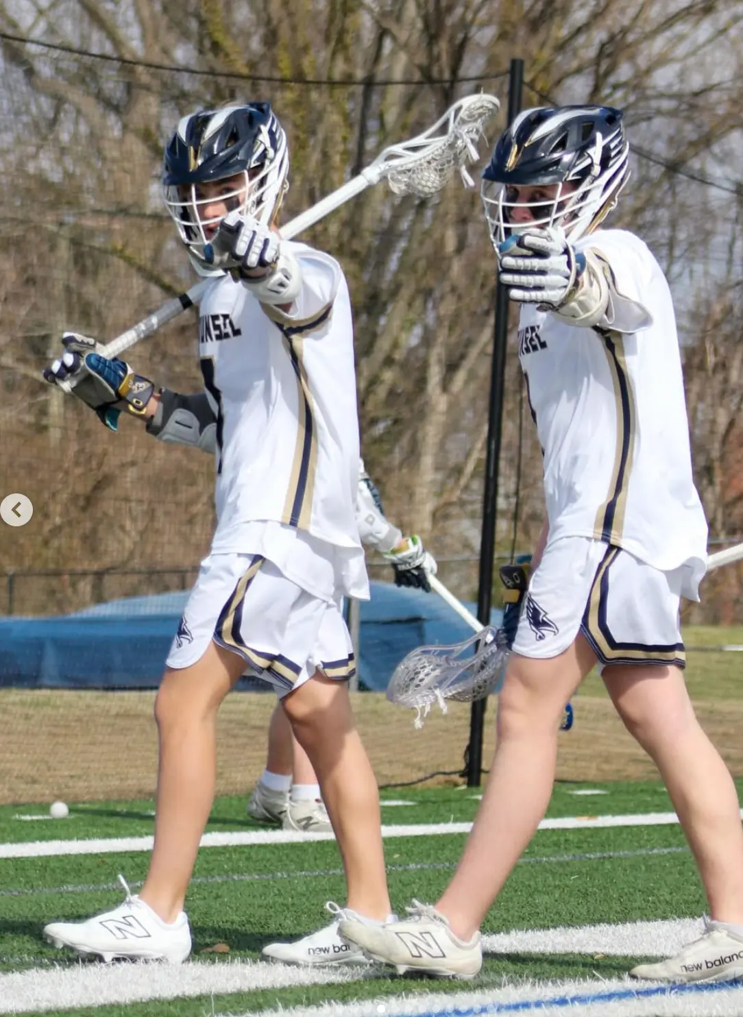 Two lacrosse players pointing out the play on the field