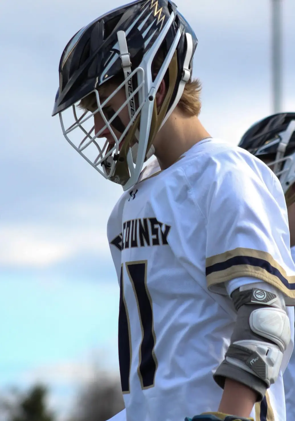 Lacrosse player in a navy helmet looking down the field